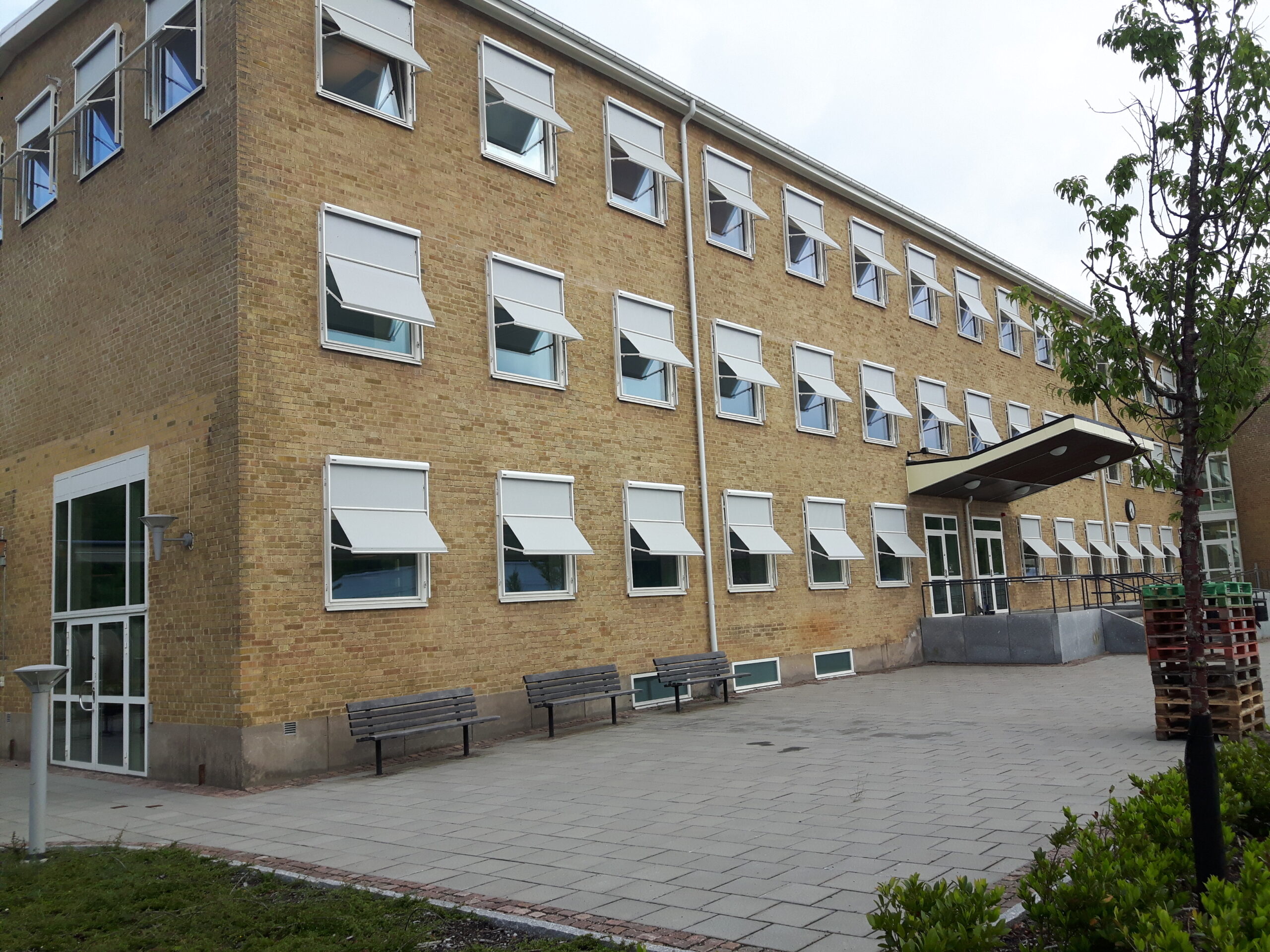 Tegelbyggnad med många vita markisoletter som är utfällda på kontorsbyggnad
