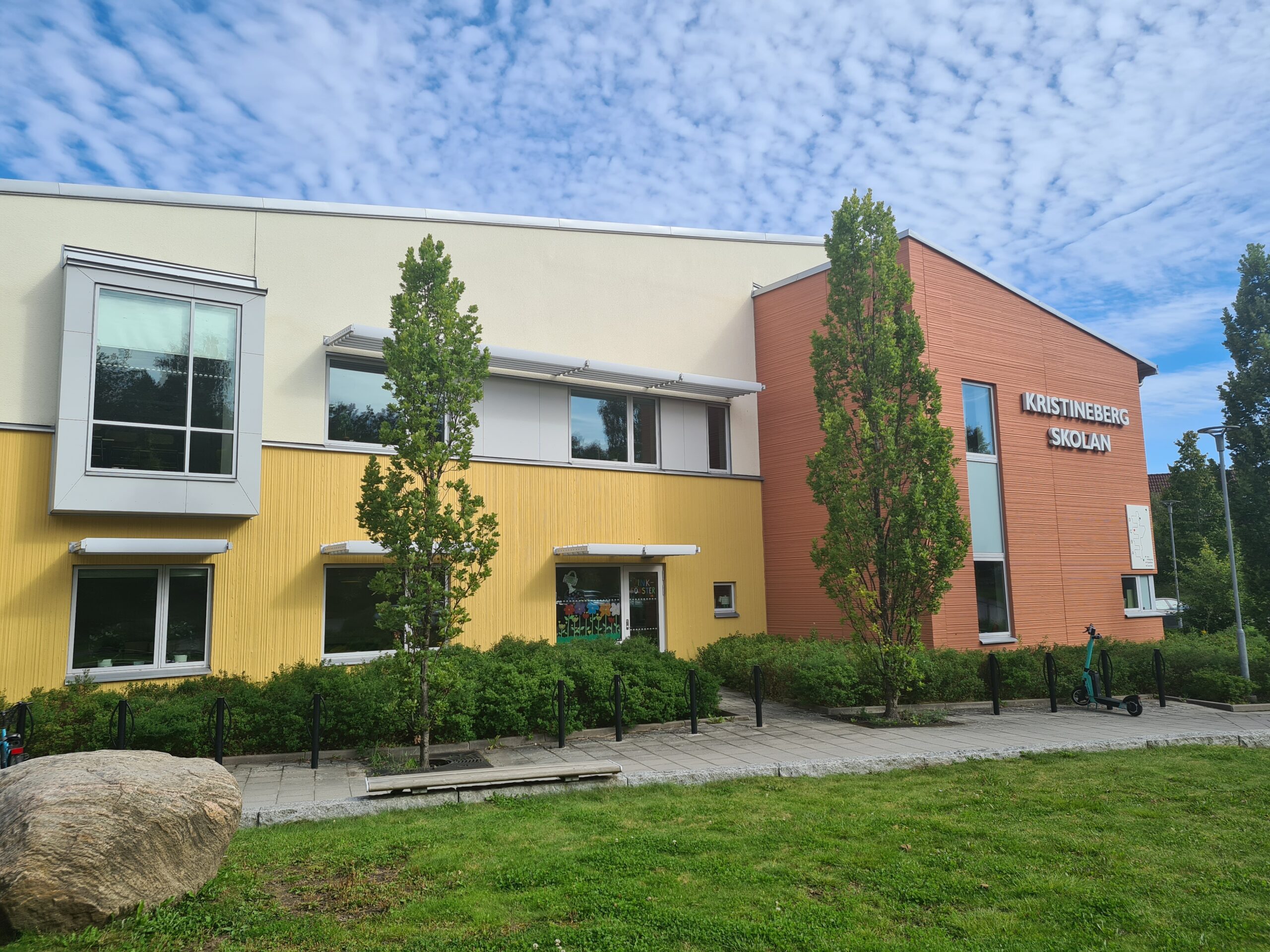Skola med horisontella solskärmar över fönster på skolbyggnadens fasad