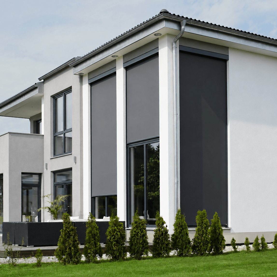 Vertikalmarkiser på höga fönster på modern villafasad, mörkgrå screen med kassett och sidoguidning över uteplats och terrass