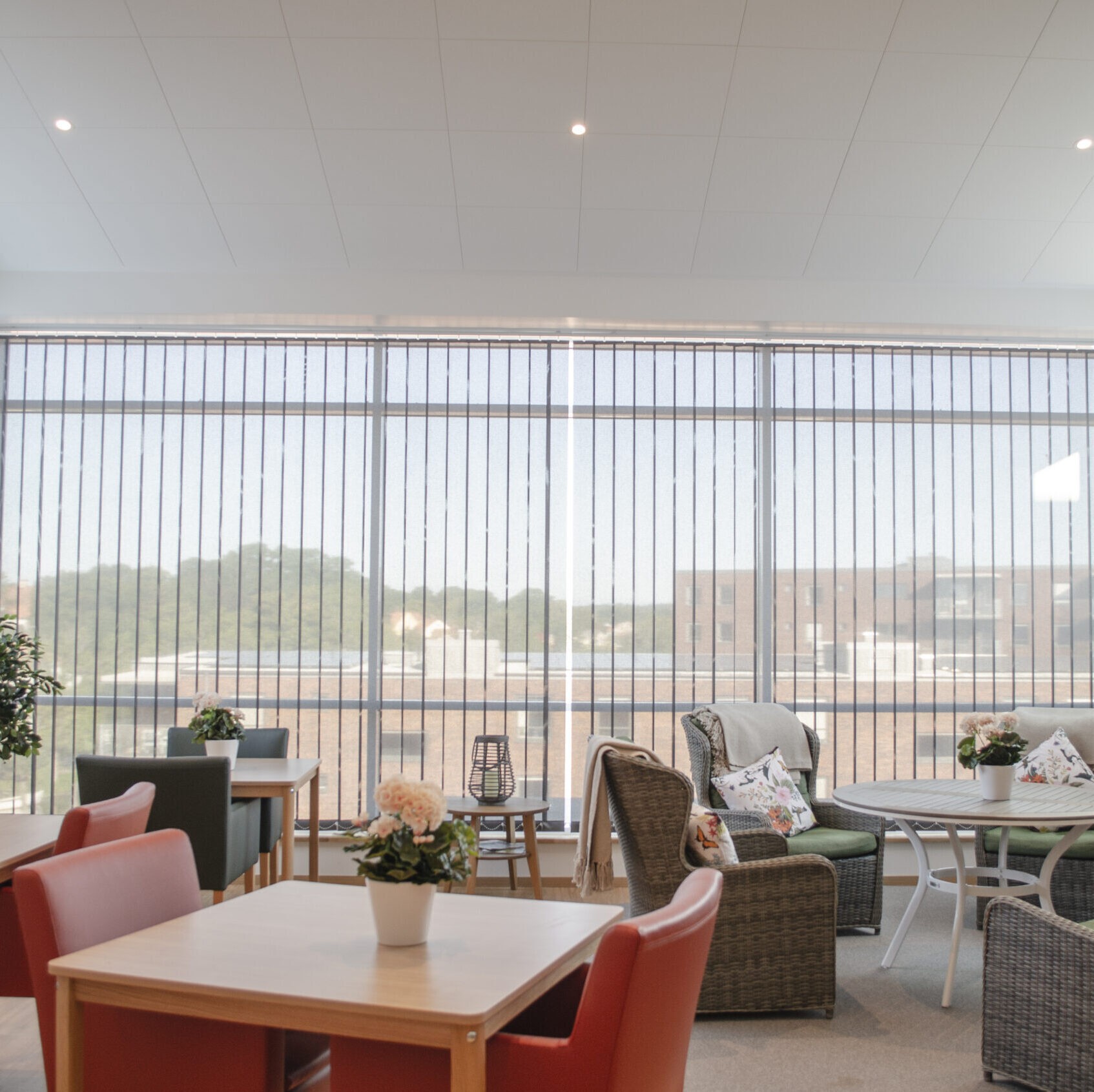 Lamellgardiner på stora fönster i ljus lounge i sällskapsrum